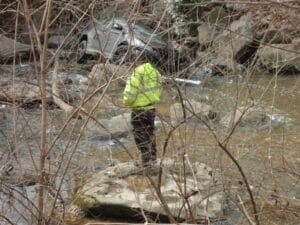 Responder in a safety vest at a vehicle recovery in a rocky ditch