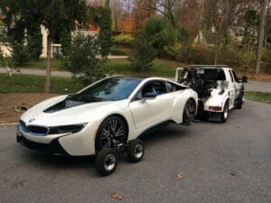 White BMW i8 on wheel dollies behind a Past & Present tow truck