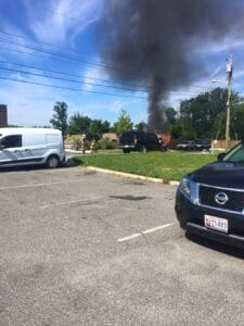 Smoke rising from a vehicle fire in a parking lot