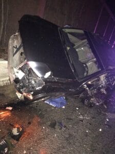 Damaged vehicle with its hood open after a night collision