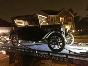 Antique Ford Model T loaded on a flatbed tow truck at night