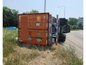 Overturned shipping container trailer on a grassy roadside