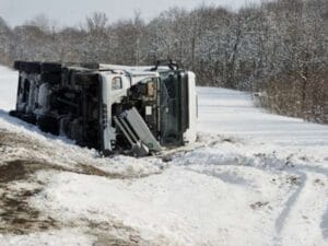 Overturned box truck in a snowy ditch before heavy recovery